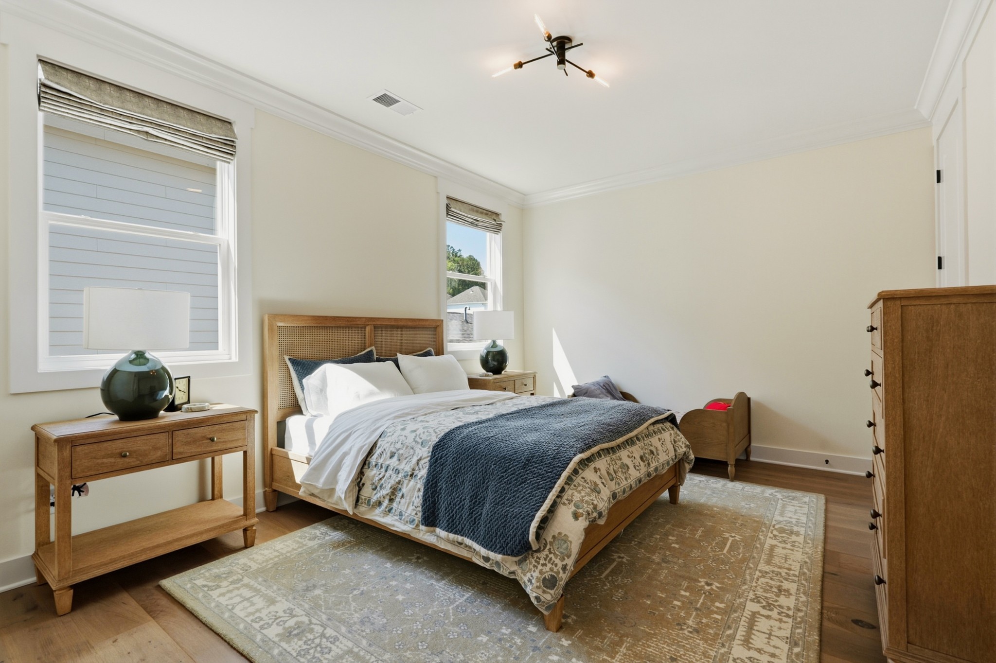Bedroom with a wood-framed bed, blue quilt, matching furniture, and a large patterned rug.