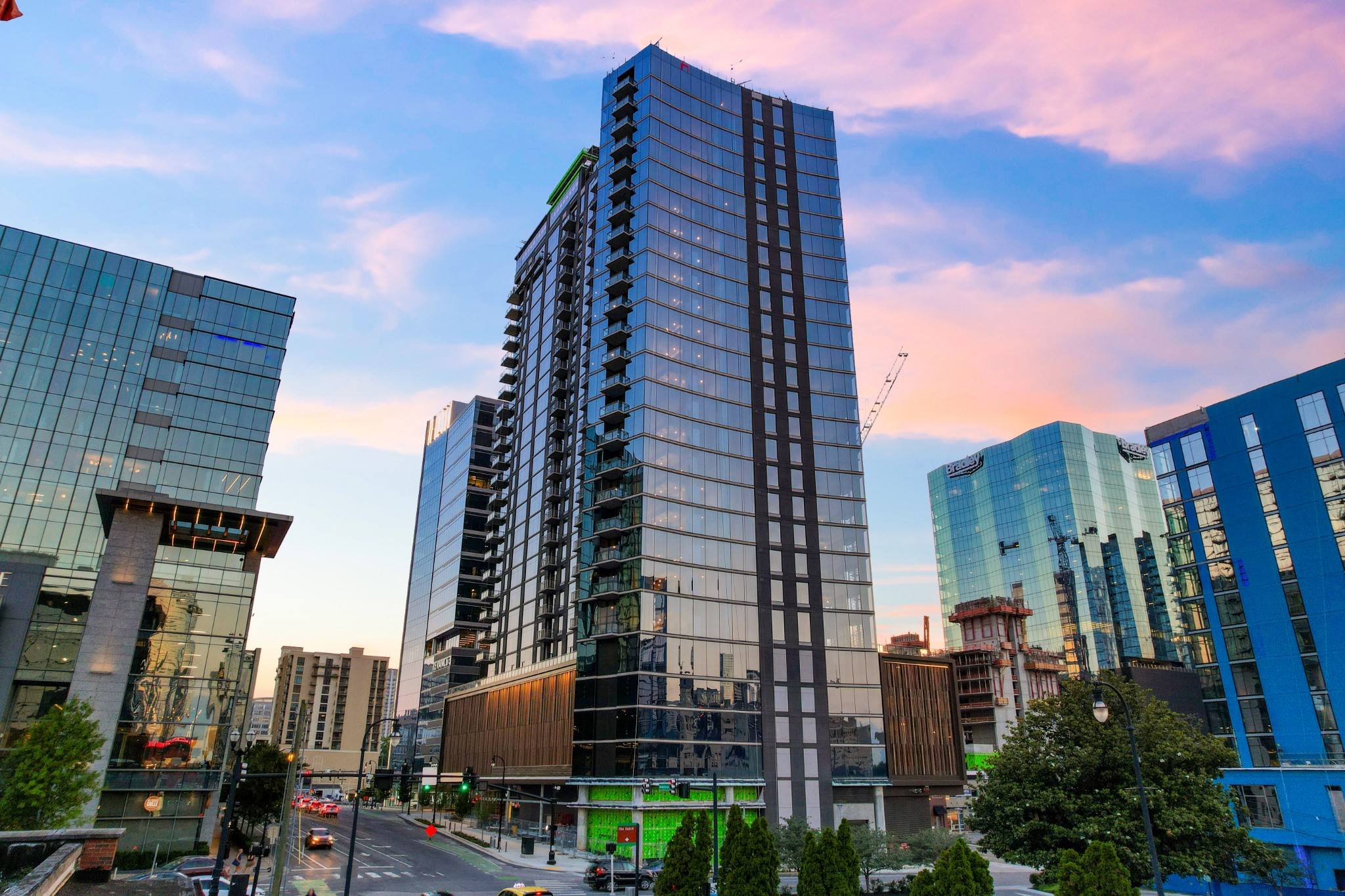 Downtown residential tower with glass balconies, neighboring high-rises, and construction visible at street level.