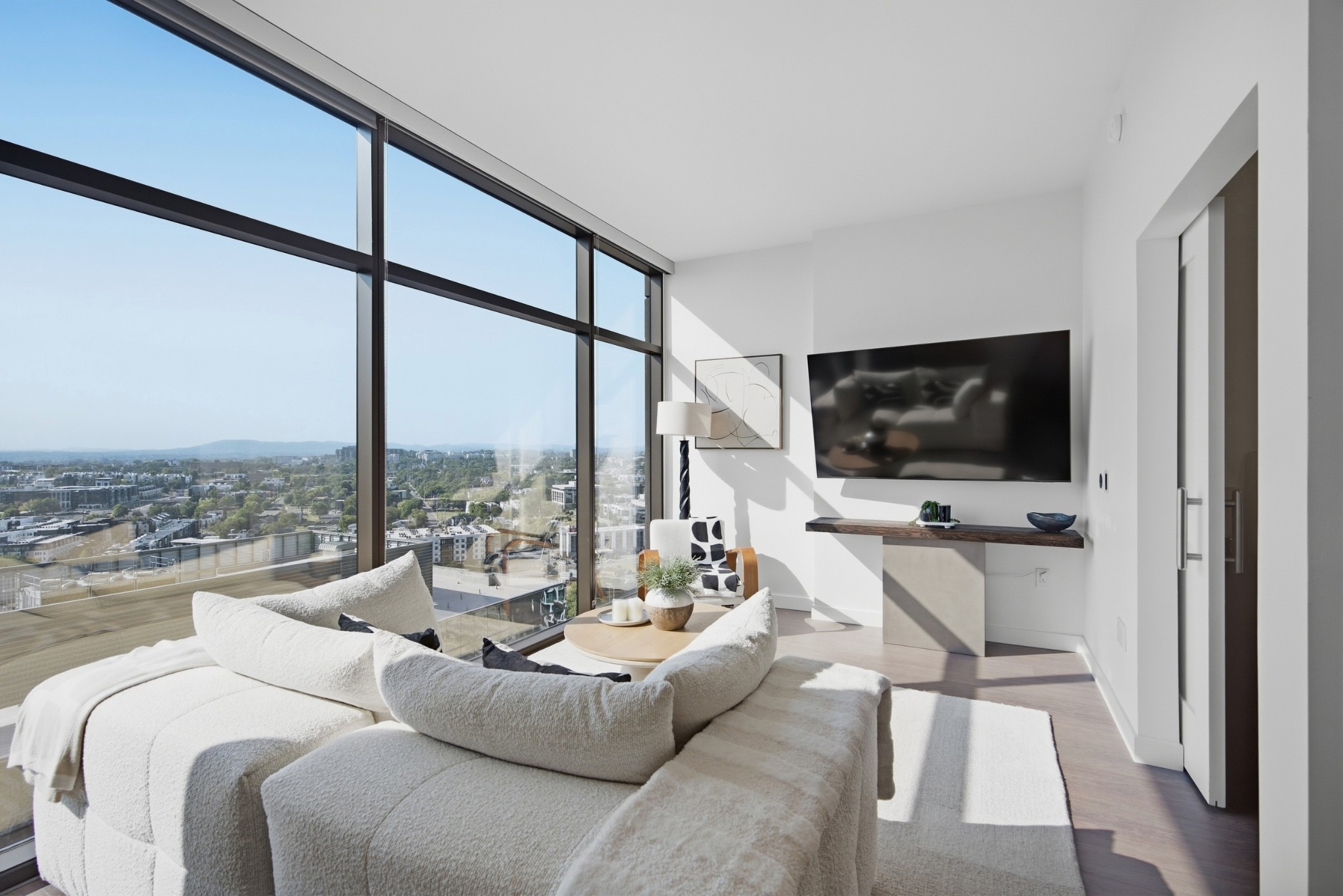 Modern condo living room with floor-to-ceiling windows and a city view.