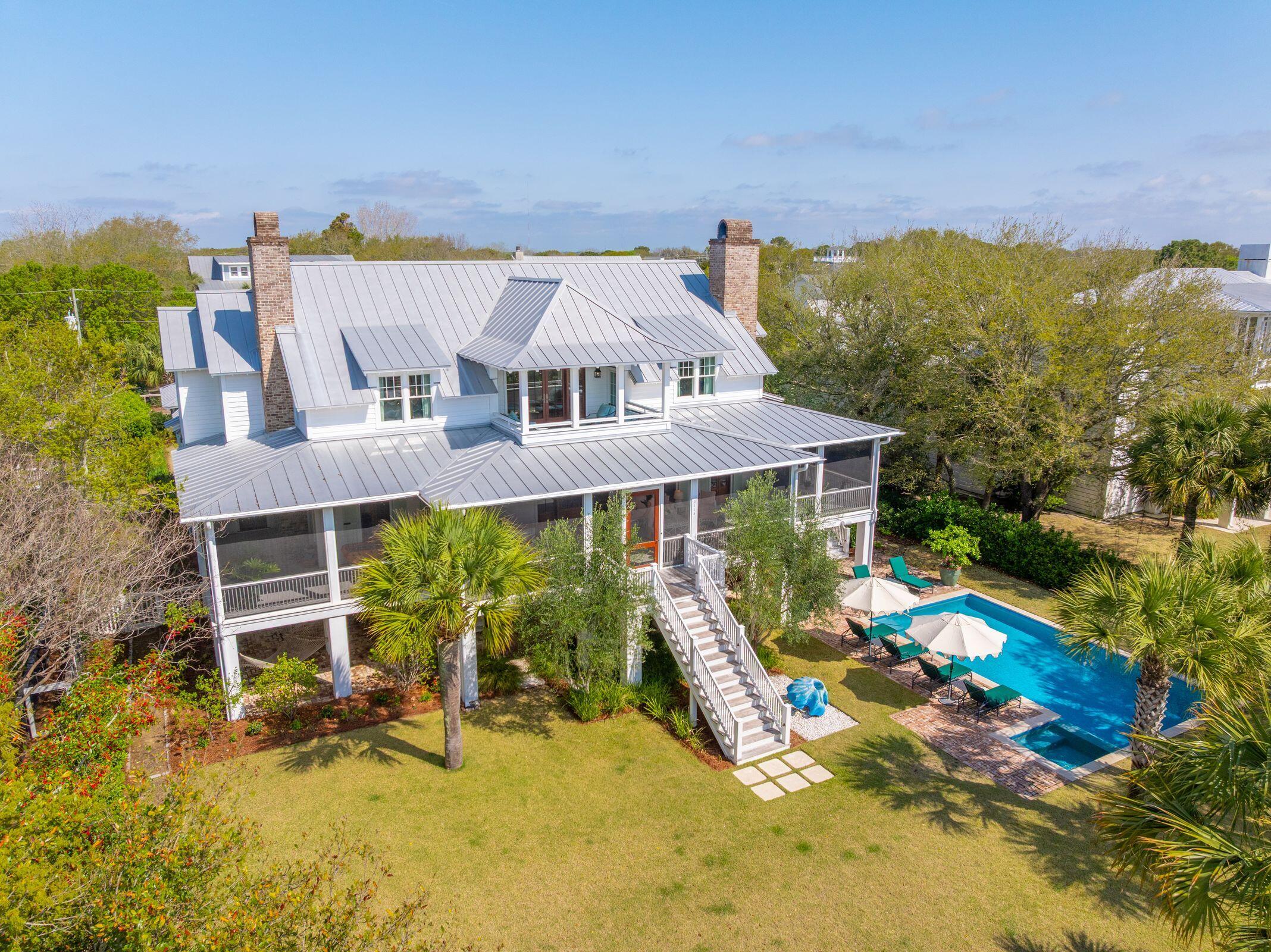 Aerial view of a white home with screened porches and a backyard pool.