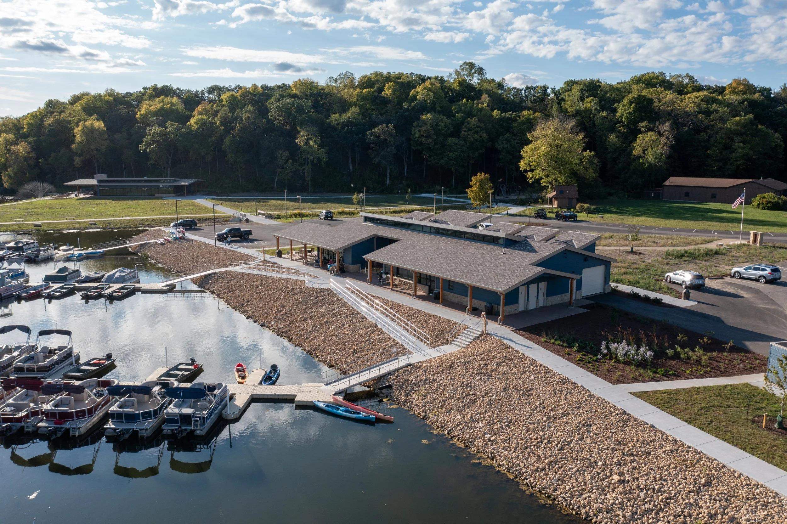 Aerial view of a marina with boat docks beside a low modern waterfront building.