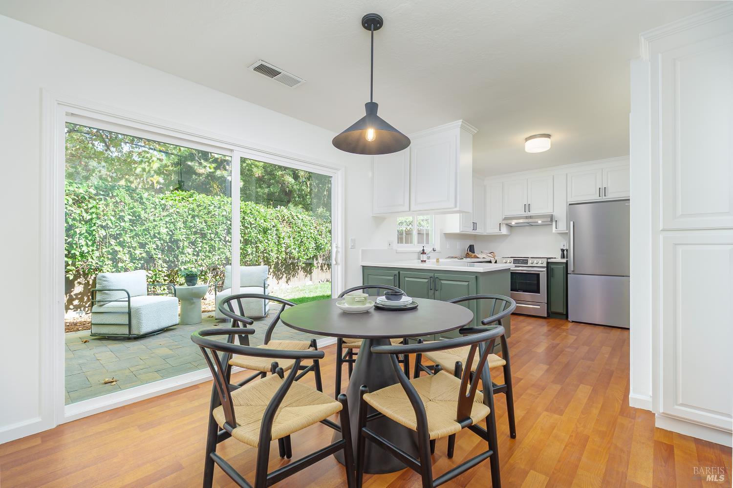 Kitchen and dining area with green lower cabinets and sliding doors to a patio.