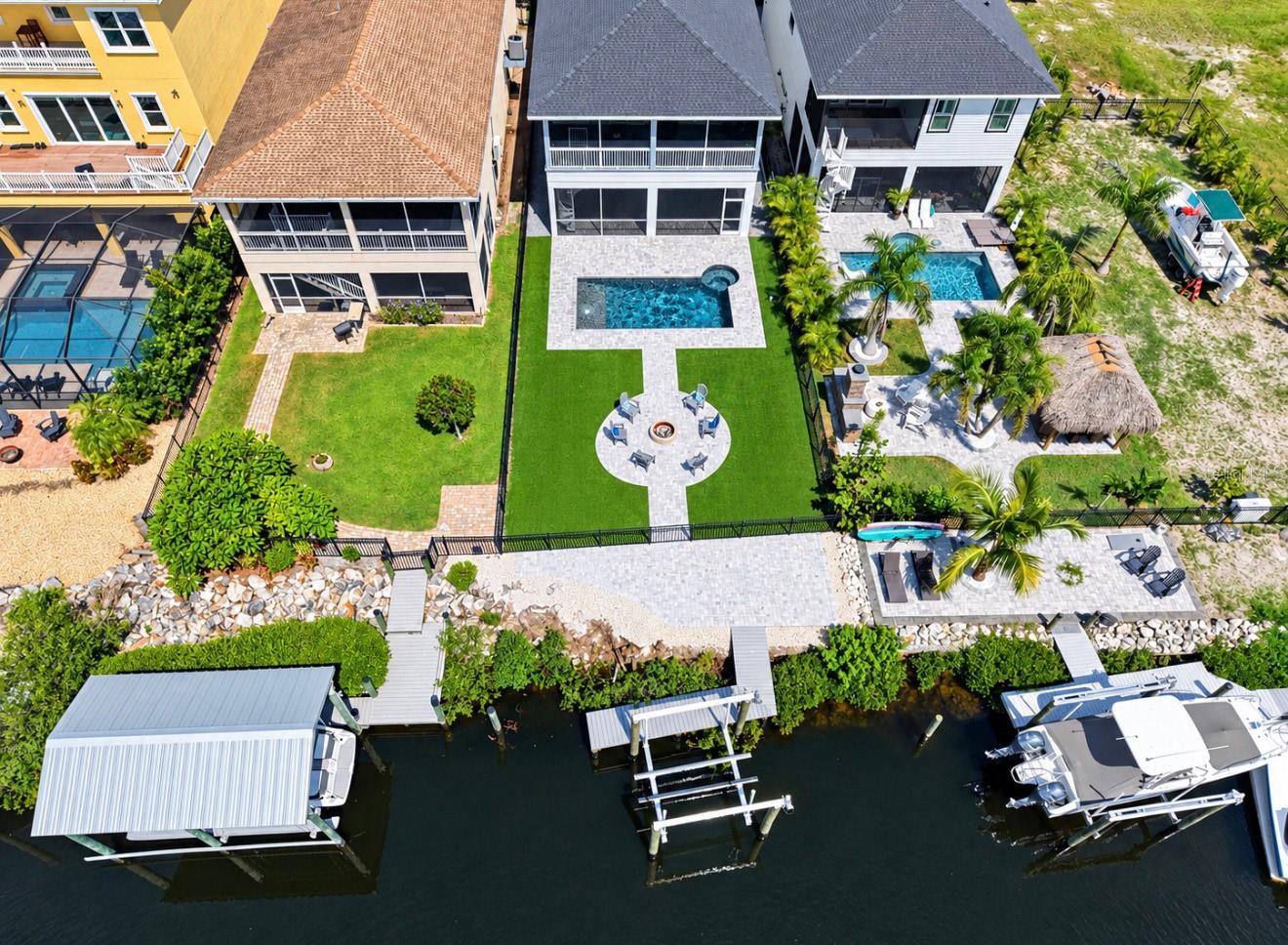 Waterfront home with a backyard pool, landscaped patio, and private dock with covered boat lift.