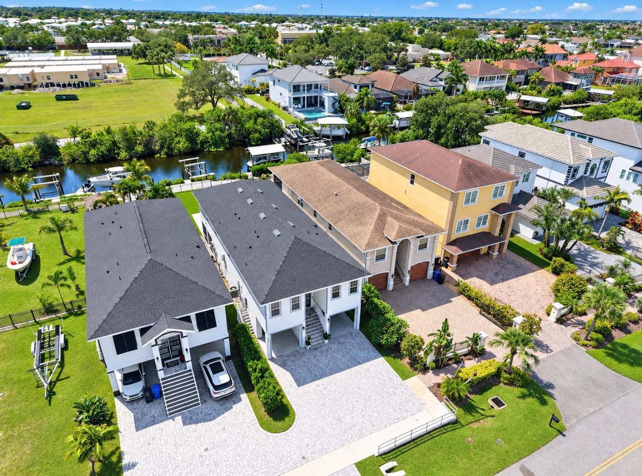 Aerial view of canal-front homes, private docks, boats, and a paved driveway.