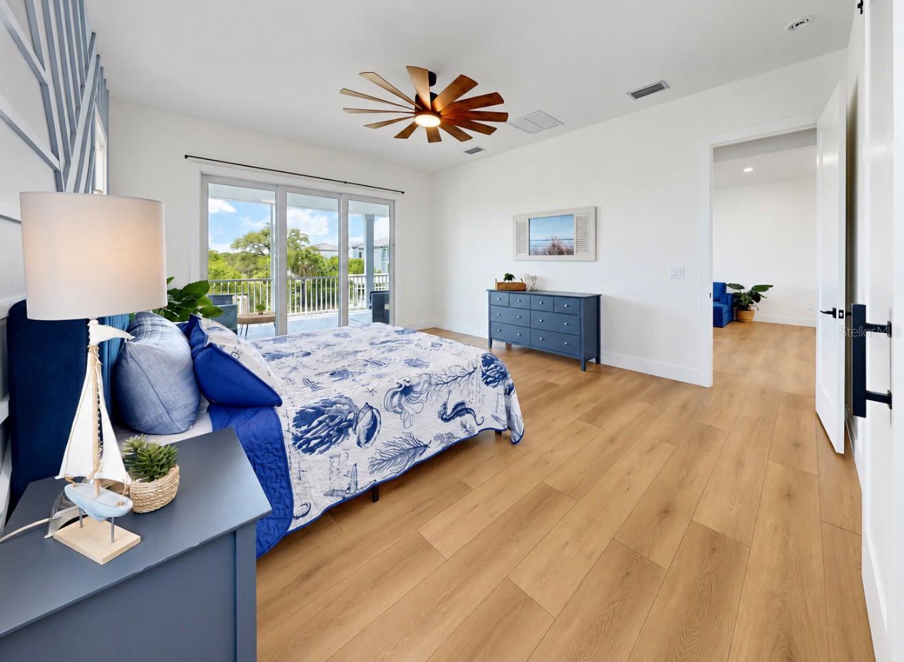 Bedroom with blue furnishings, patterned bedding, wood floors, and sliding doors to a balcony.