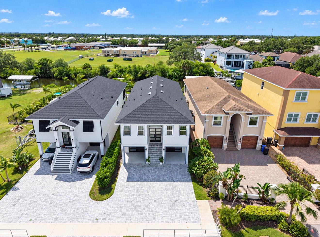 Two-story gray home with a dark roof, two garage bays, and a broad paved driveway.