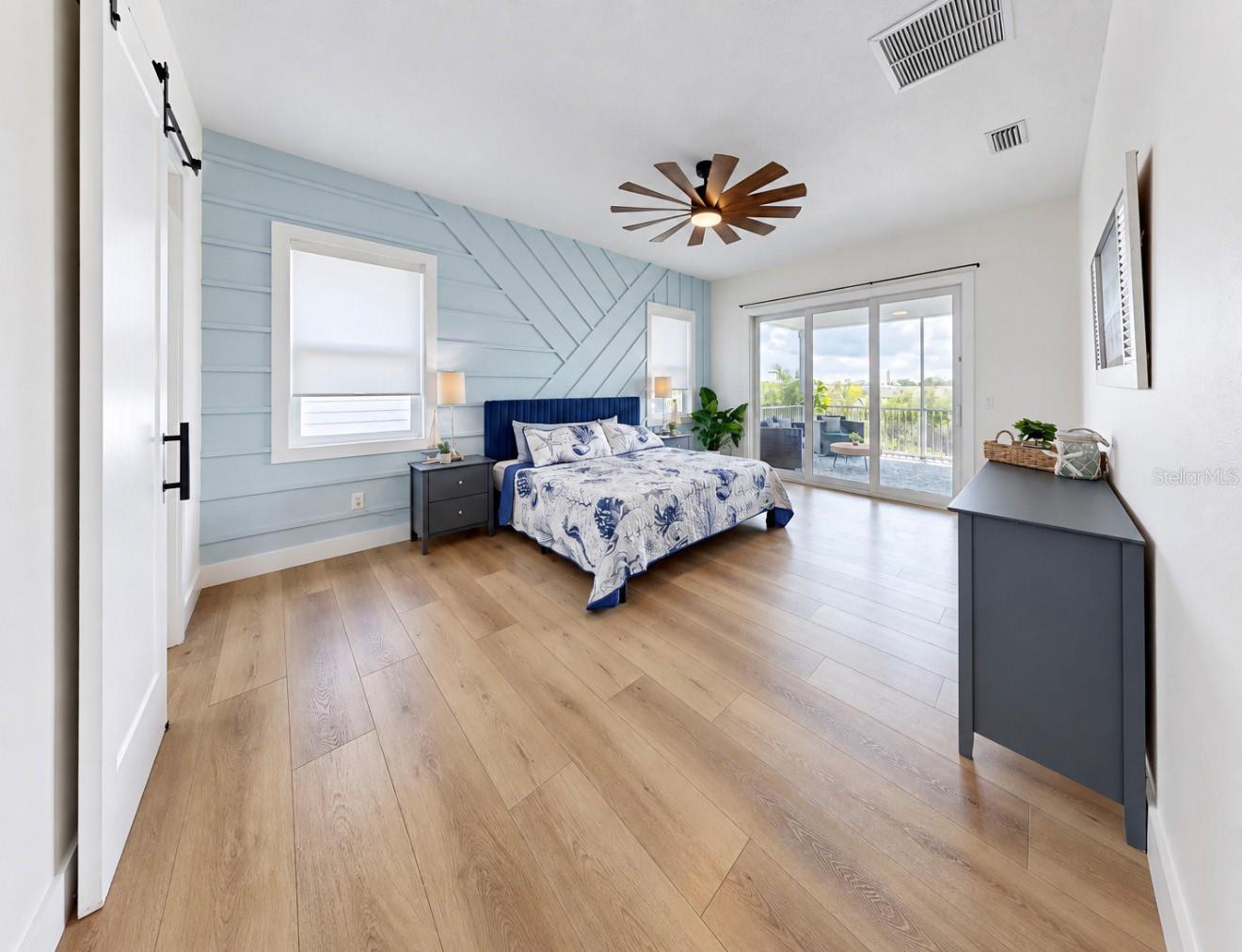 Bedroom with a blue geometric accent wall, blue-and-white bedding, and sliding doors to a balcony.