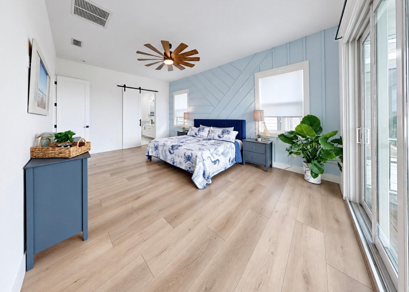 Bedroom with a blue geometric accent wall, upholstered bed, and large sliding glass doors.