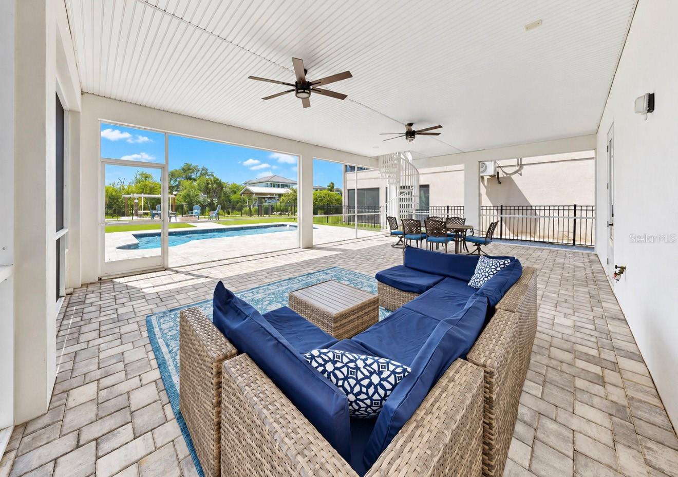 Covered patio with blue wicker seating and a pool view.