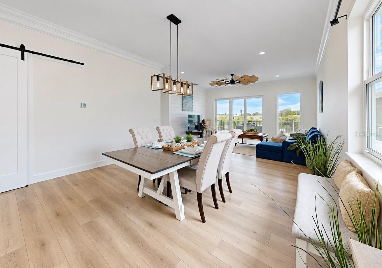 Open-plan dining and living room with a large table, blue sofa, and balcony doors.