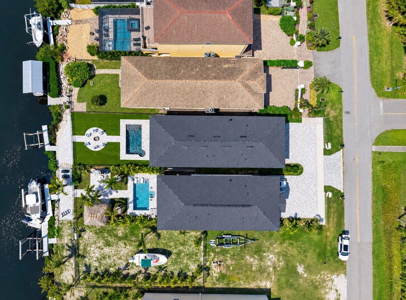 Waterfront home with a backyard pool, private dock, and boats along the canal.