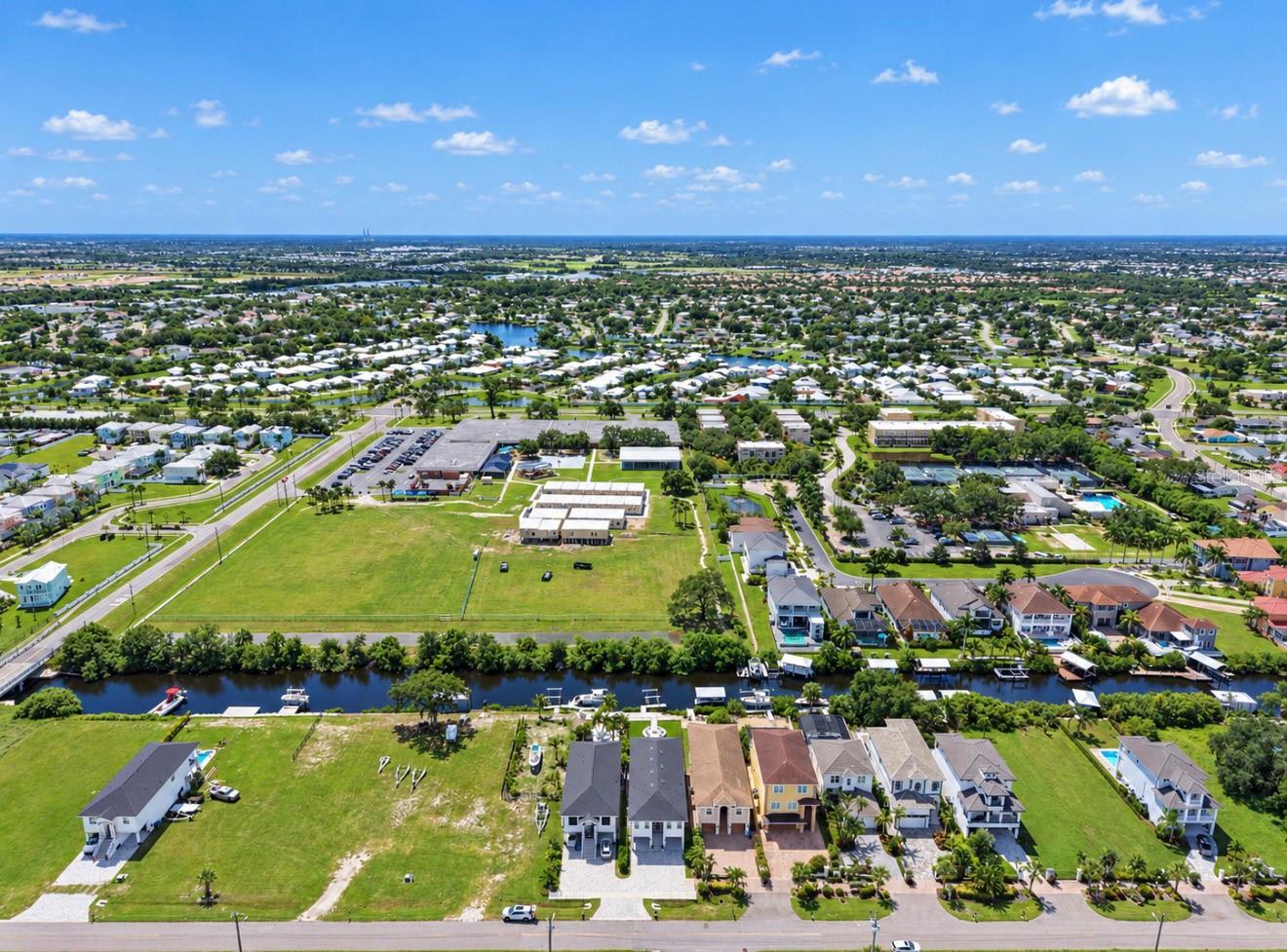 Aerial view of waterfront homes, a canal, and a vacant lot in a suburban community.