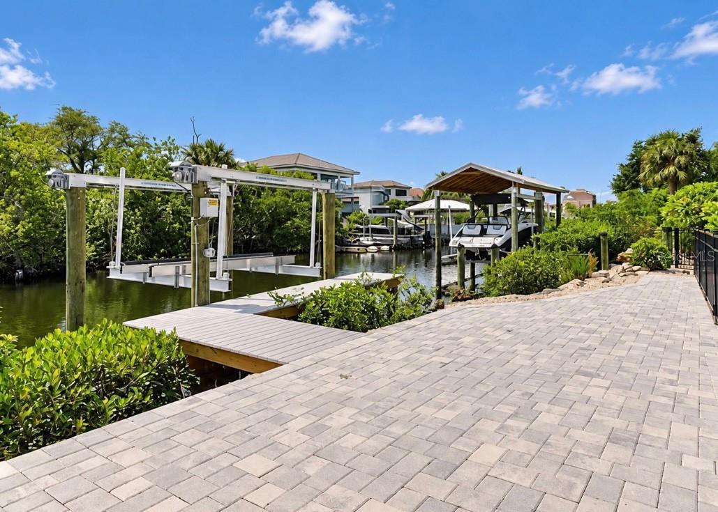 Canal-side patio with a dock, boat lift, and covered boat slip.
