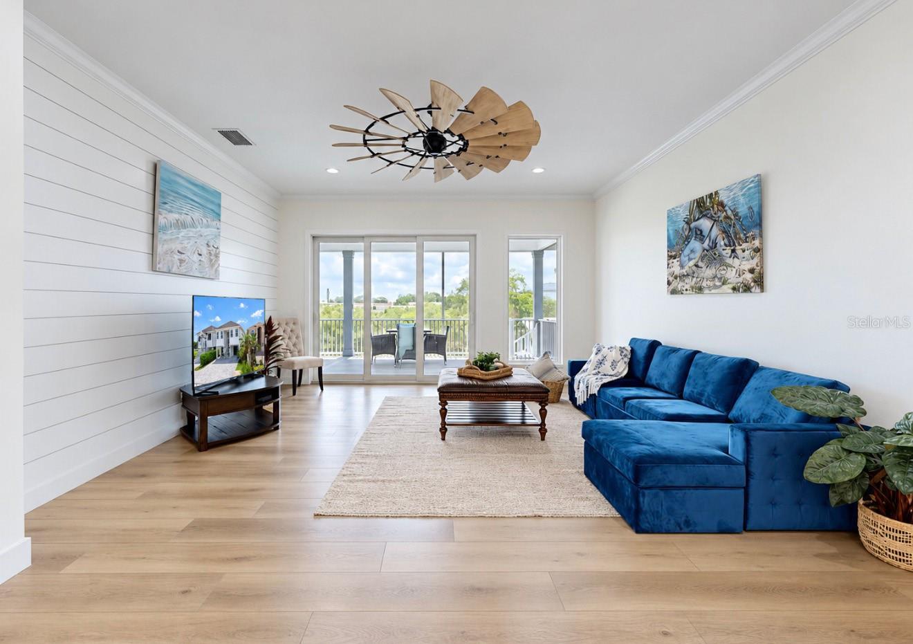 Living room with a blue sectional, shiplap accent wall, and sliding glass doors to a patio.