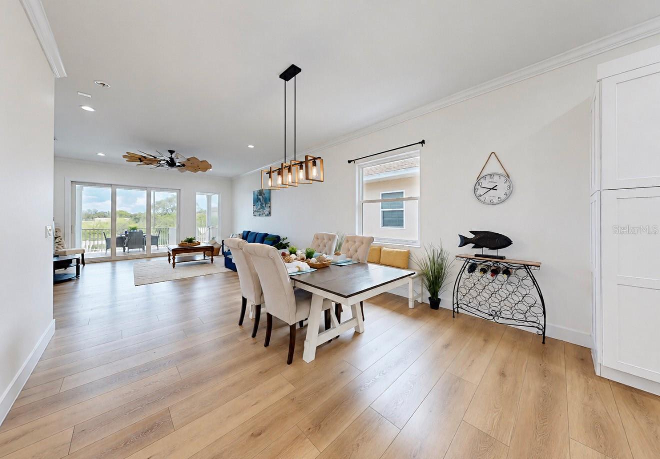 Open-plan dining and living room with light wood floors and sliding glass doors to a balcony.
