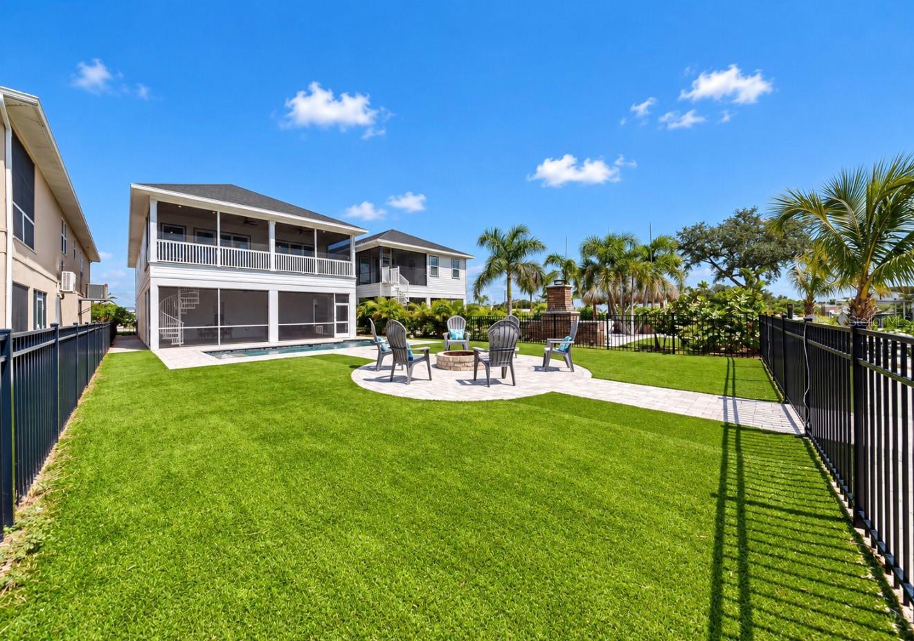 Two-story home behind a broad lawn, with a screened patio and a fire pit seating area.