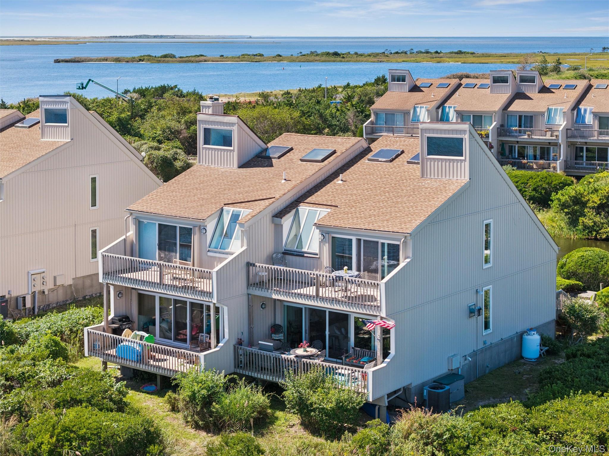 Waterfront townhouse with multiple balconies and rooftop windows overlooking a bay.