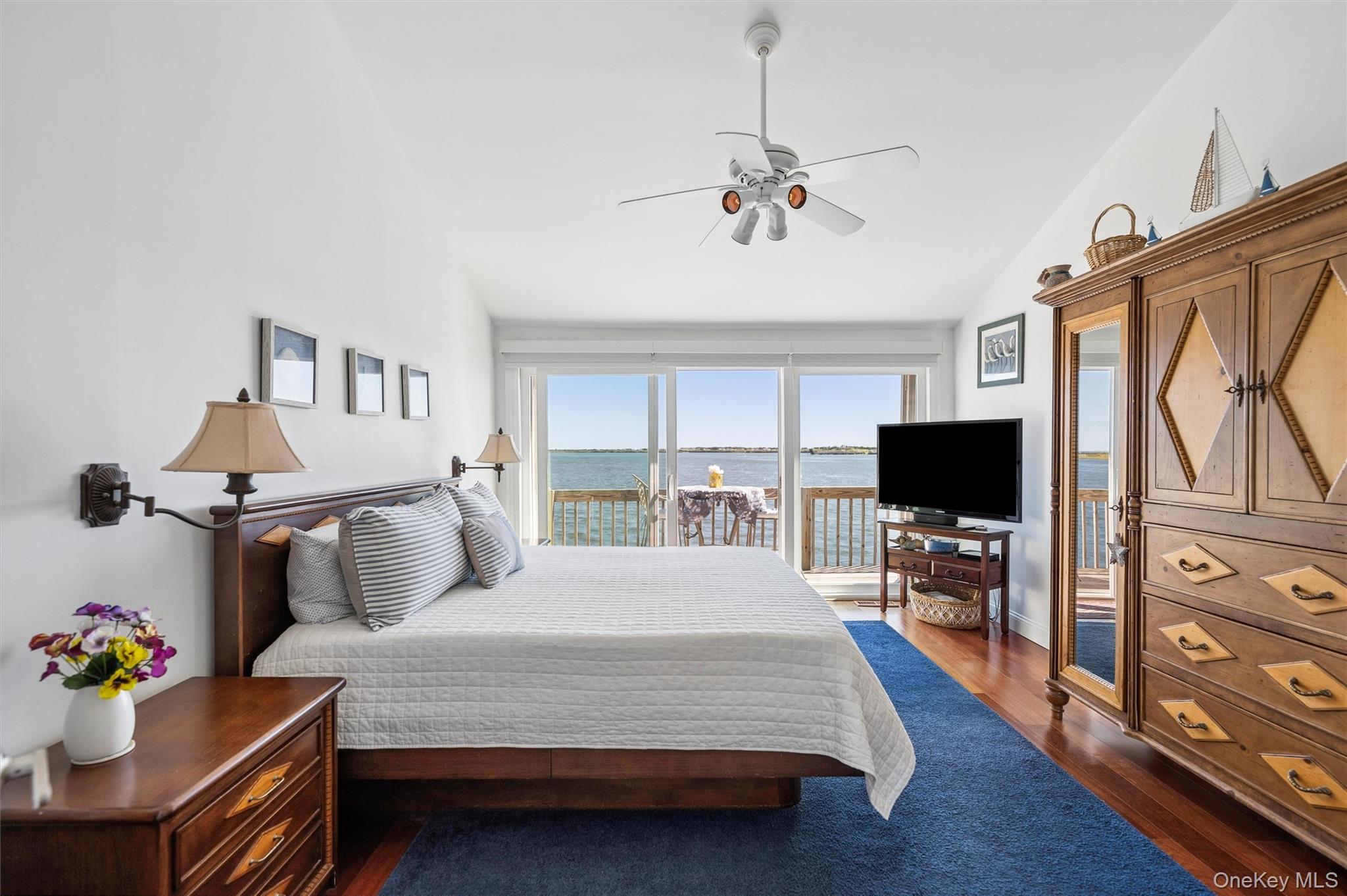 Bedroom with a water view through sliding glass doors and a furnished deck.
