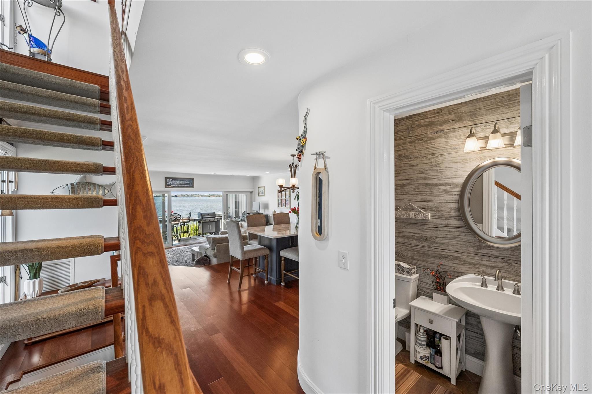 Furnished home interior with staircase, powder room, and dining area overlooking the water.