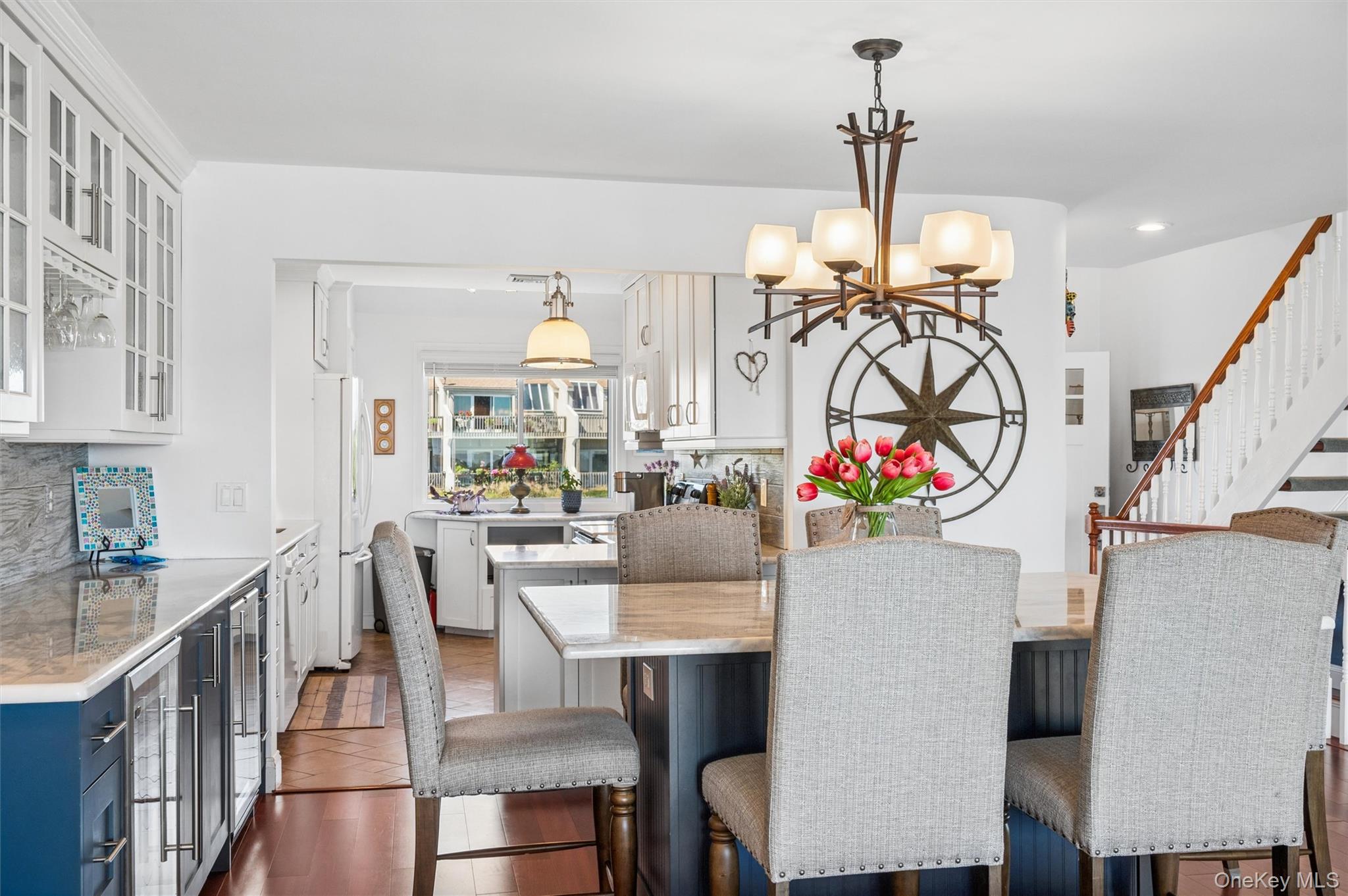 Kitchen and dining area with white cabinetry, blue lower cabinets, a large table, and a staircase.
