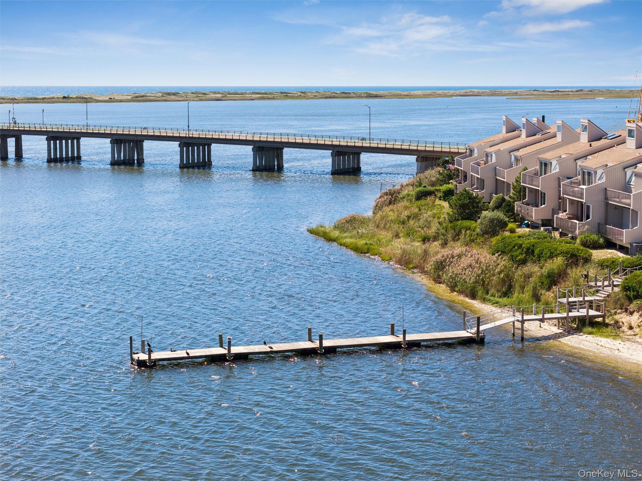 Waterfront townhouses beside a bridge, with a dock extending over the water.