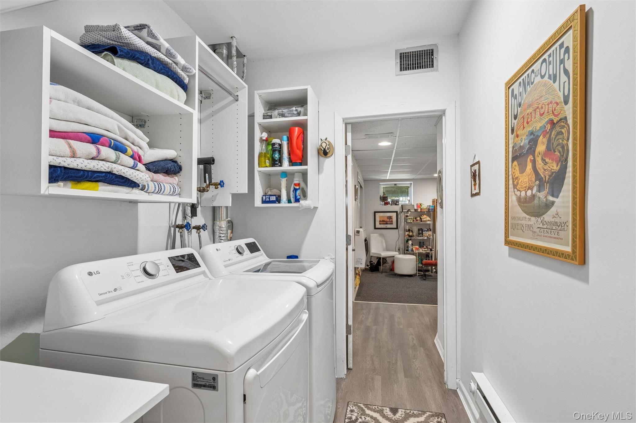 Laundry room with washer and dryer beneath open shelves of folded towels.
