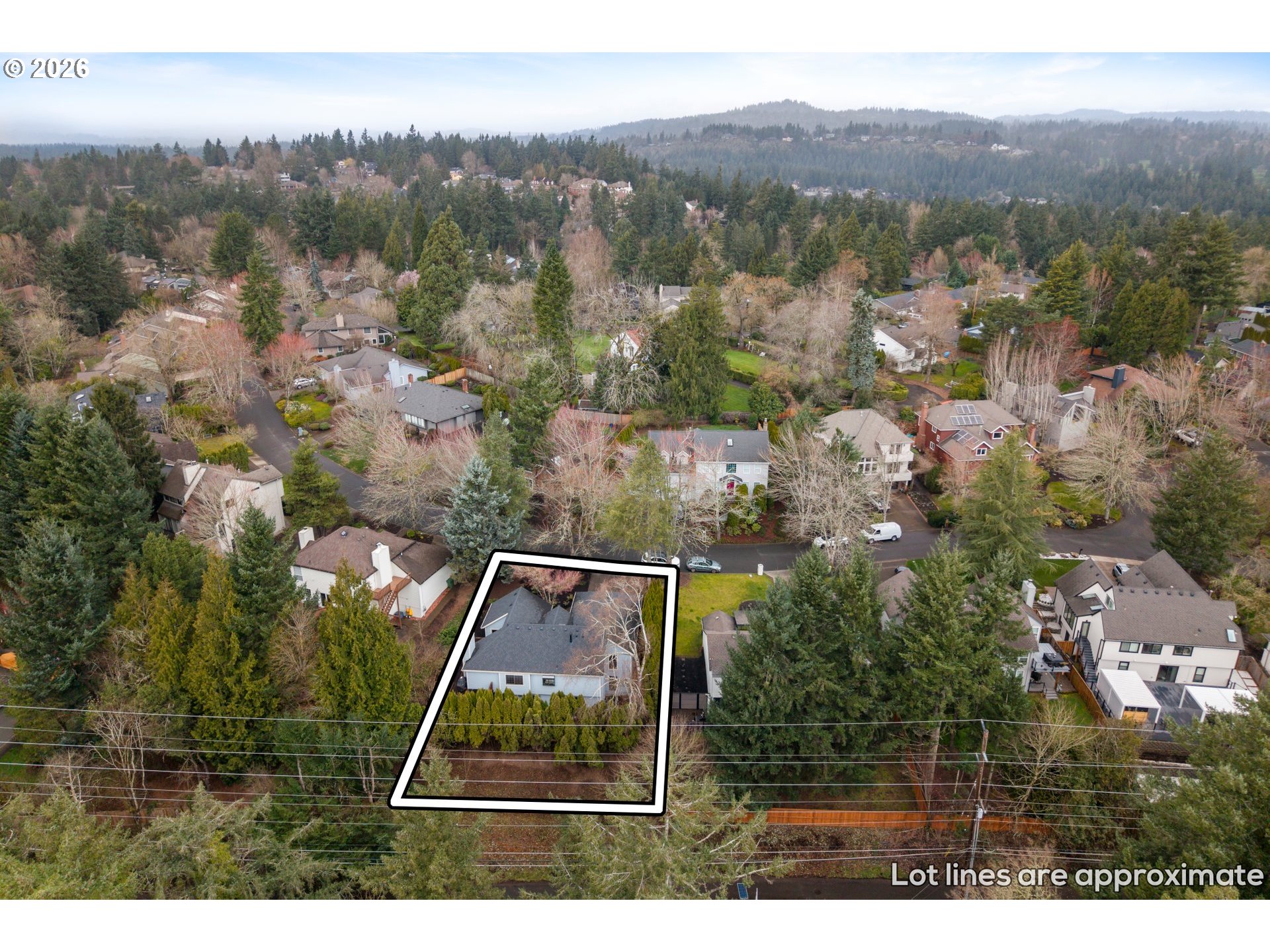 Aerial view of a home and its approximate lot lines amid a wooded residential neighborhood.