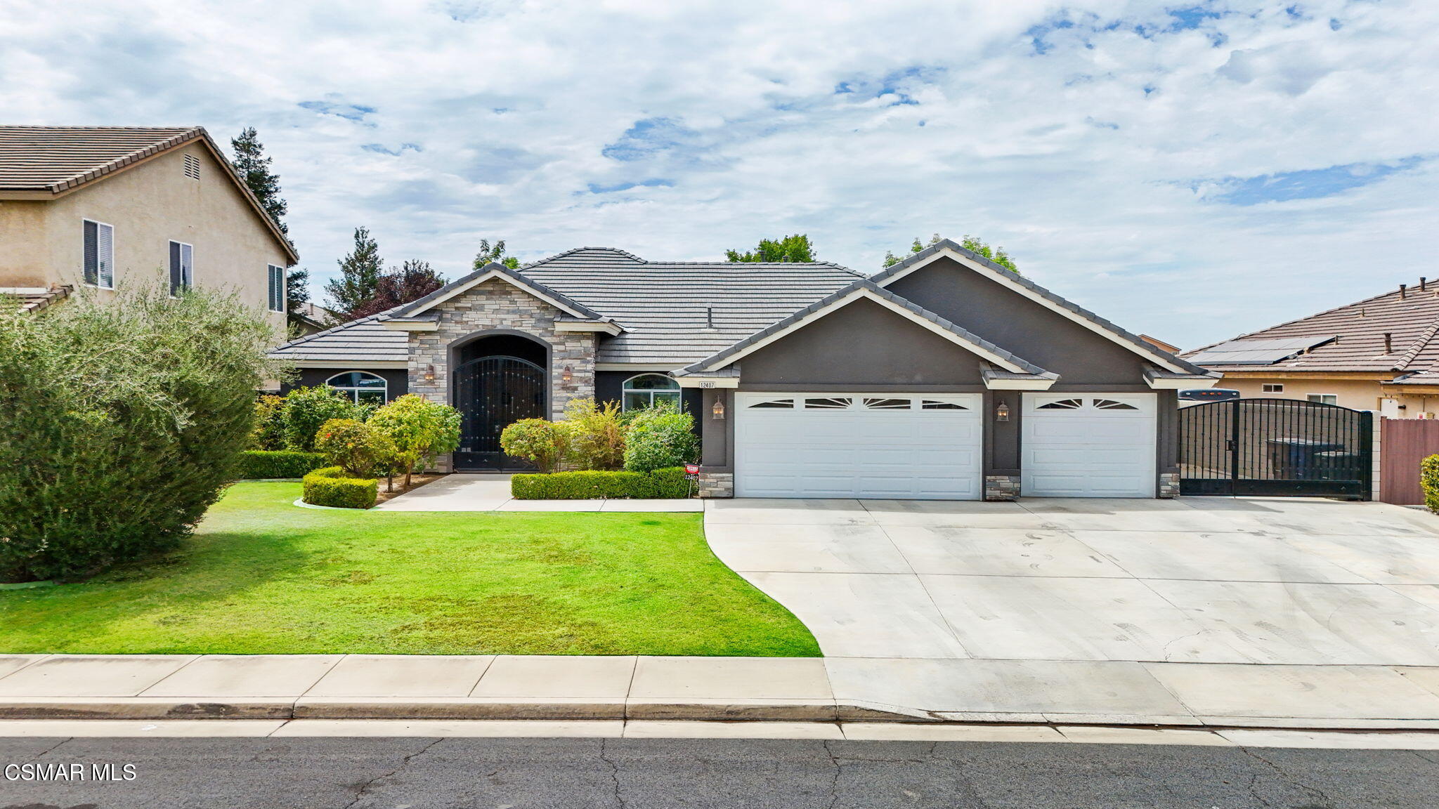 Single-story home with stone accents, a three-car garage, and a landscaped front lawn.