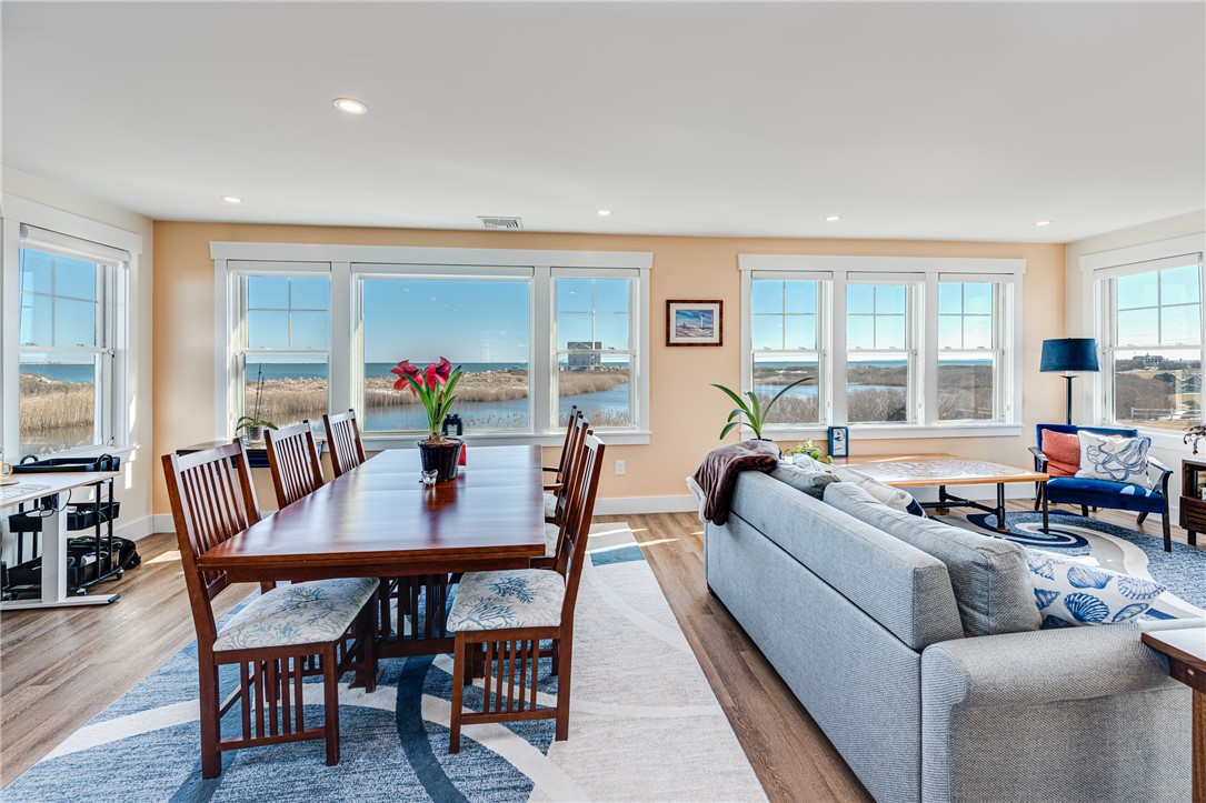 Open-plan living and dining room with expansive windows overlooking coastal water and marshland.