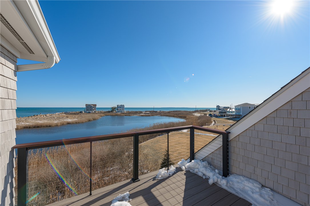 Elevated deck overlooking a marsh pond and the ocean, with snow patches on the boards.