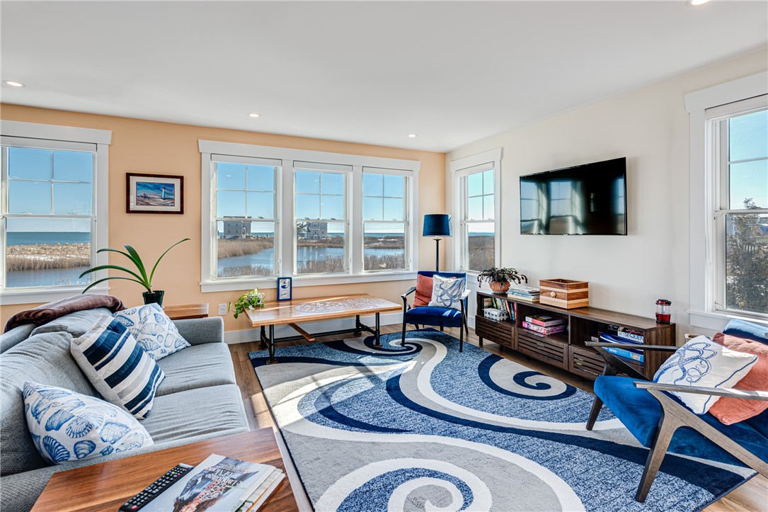 Furnished living room with large windows overlooking a coastal inlet and ocean.