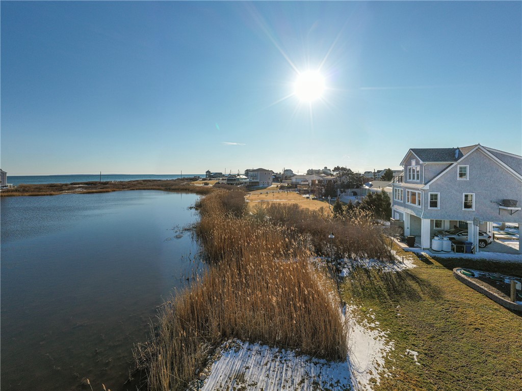 Coastal house beside a reed-lined salt pond, with the ocean visible in the distance.