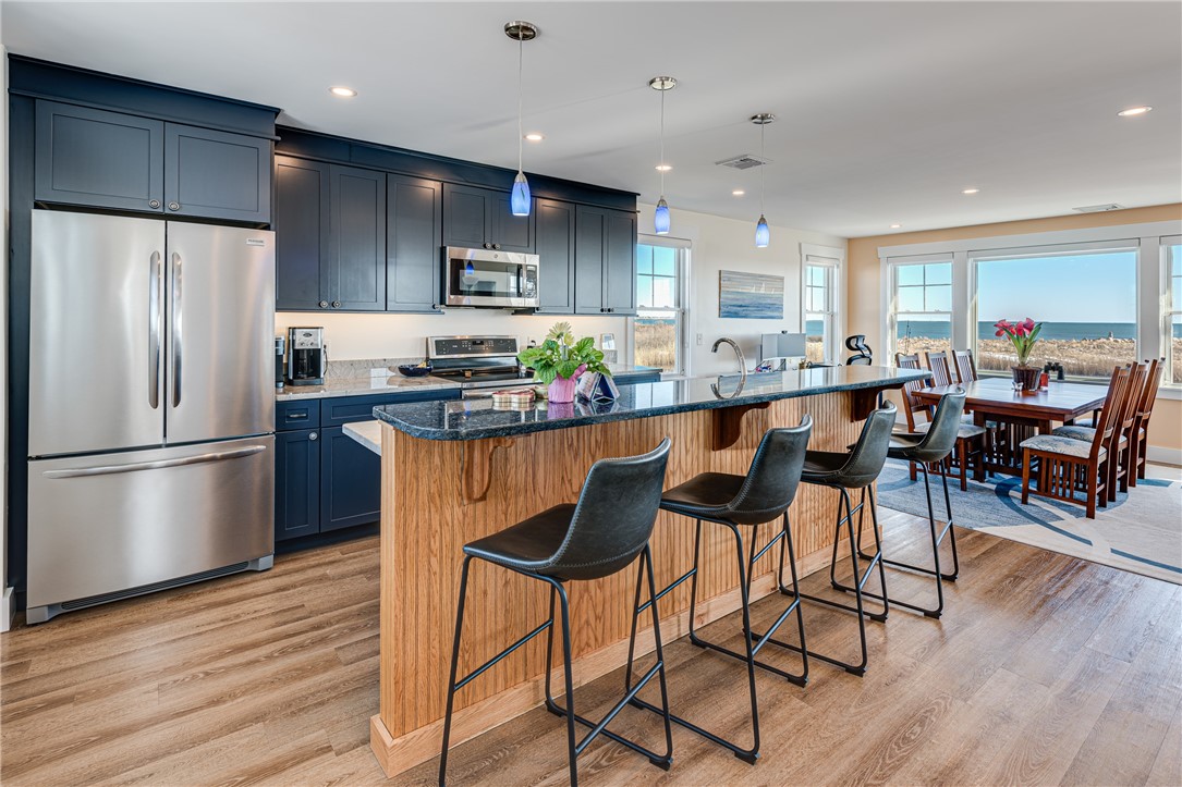 Kitchen with a wood-paneled island and ocean views through the dining area windows.