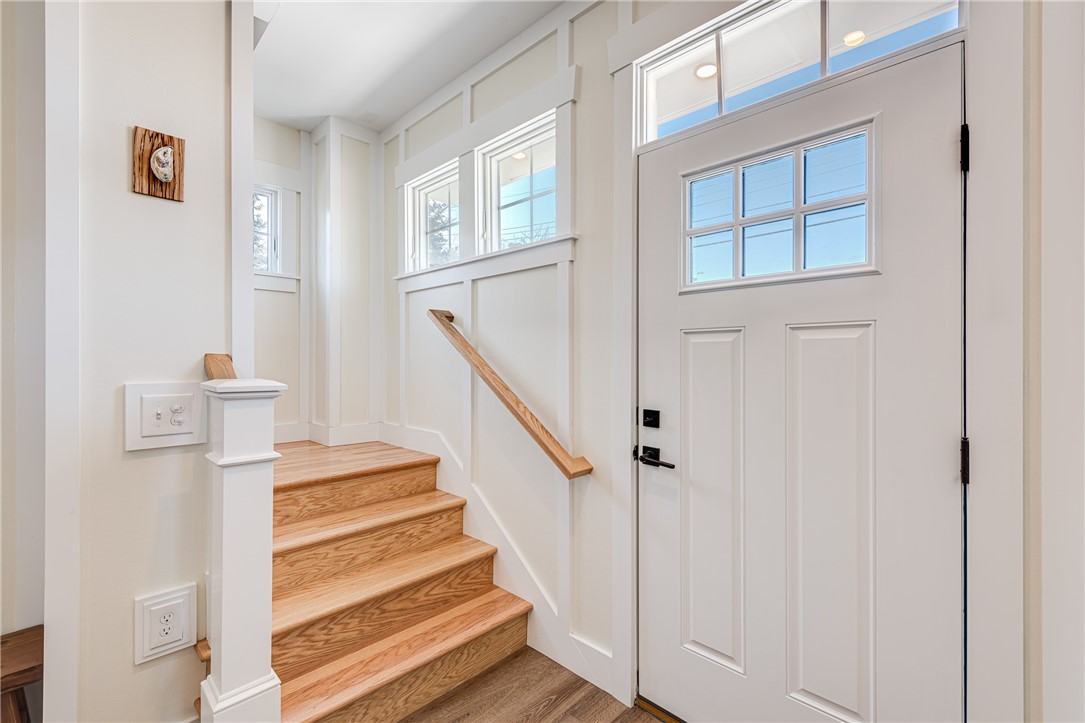 Entry foyer with a glass-paneled white front door and oak stairs.