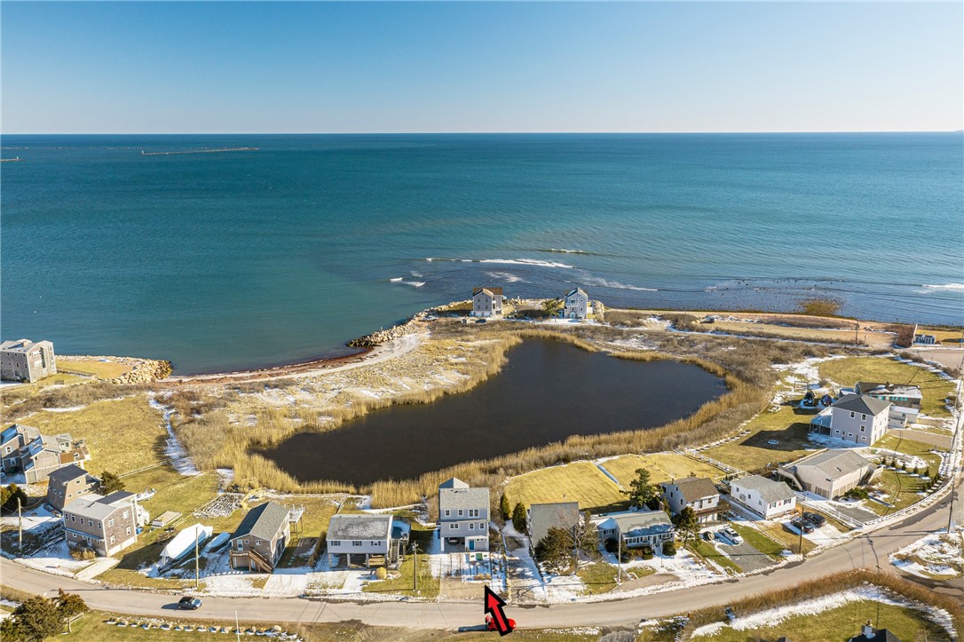 Aerial view of a coastal home beside a marsh, with the ocean beyond.
