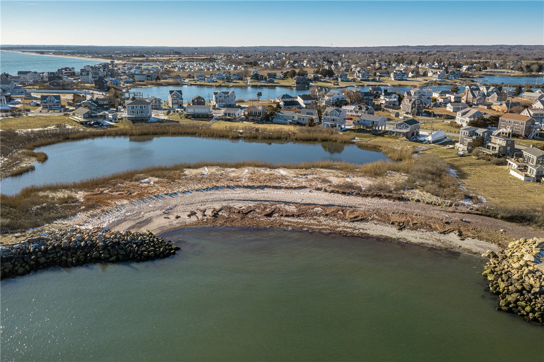 Aerial view of a rocky shoreline, marsh pond, and coastal homes.