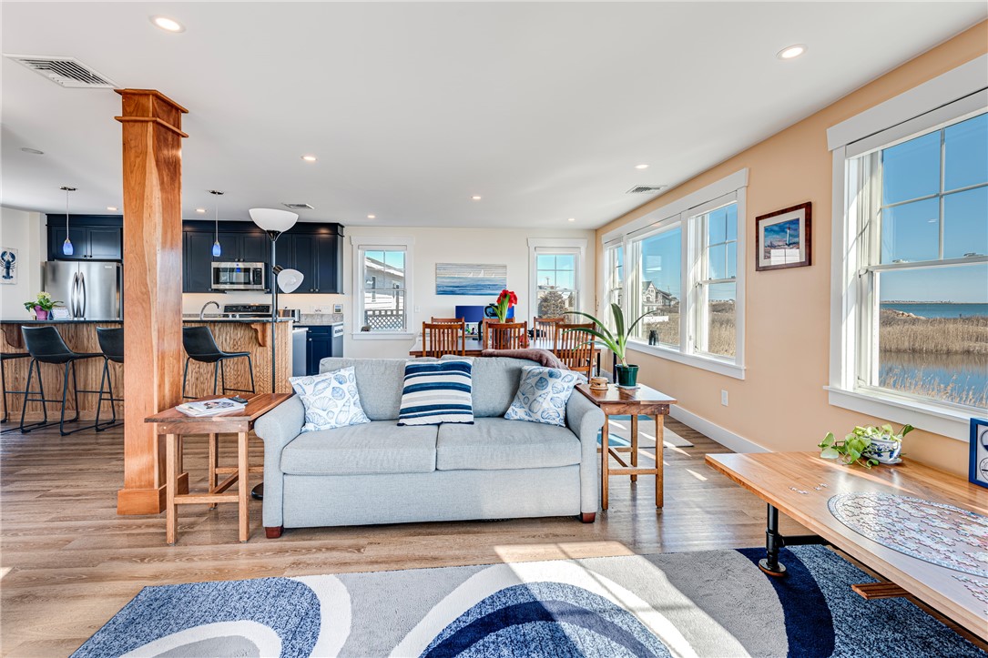 Open-plan living room with a gray sofa and large windows overlooking the water.