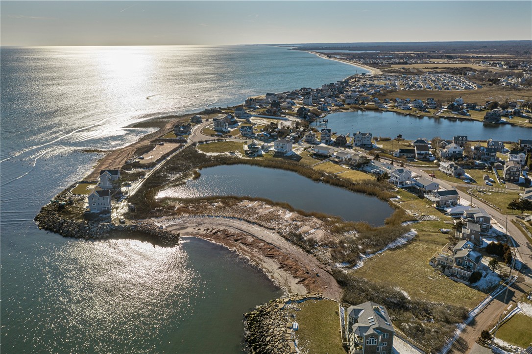 Aerial view of coastal homes beside the ocean, a tidal pond, and marshland.