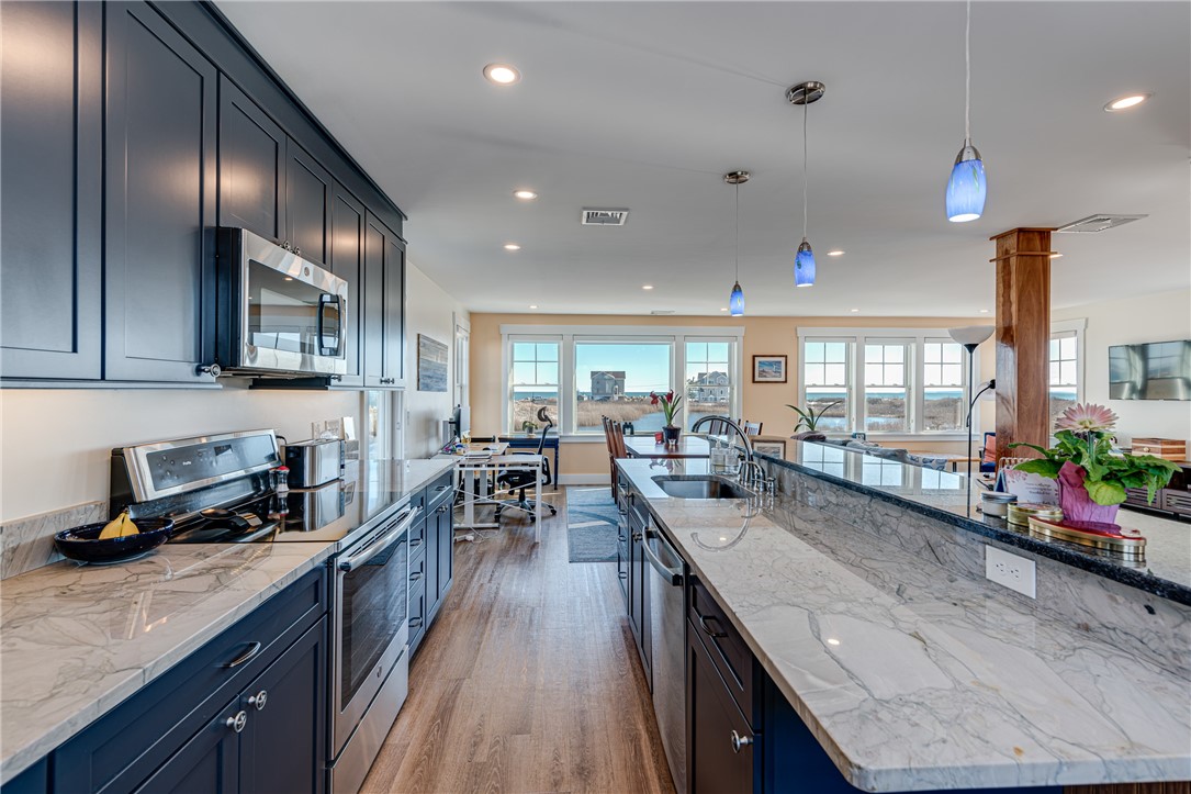 Kitchen with dark blue cabinets and a marble island, with water visible through the windows.