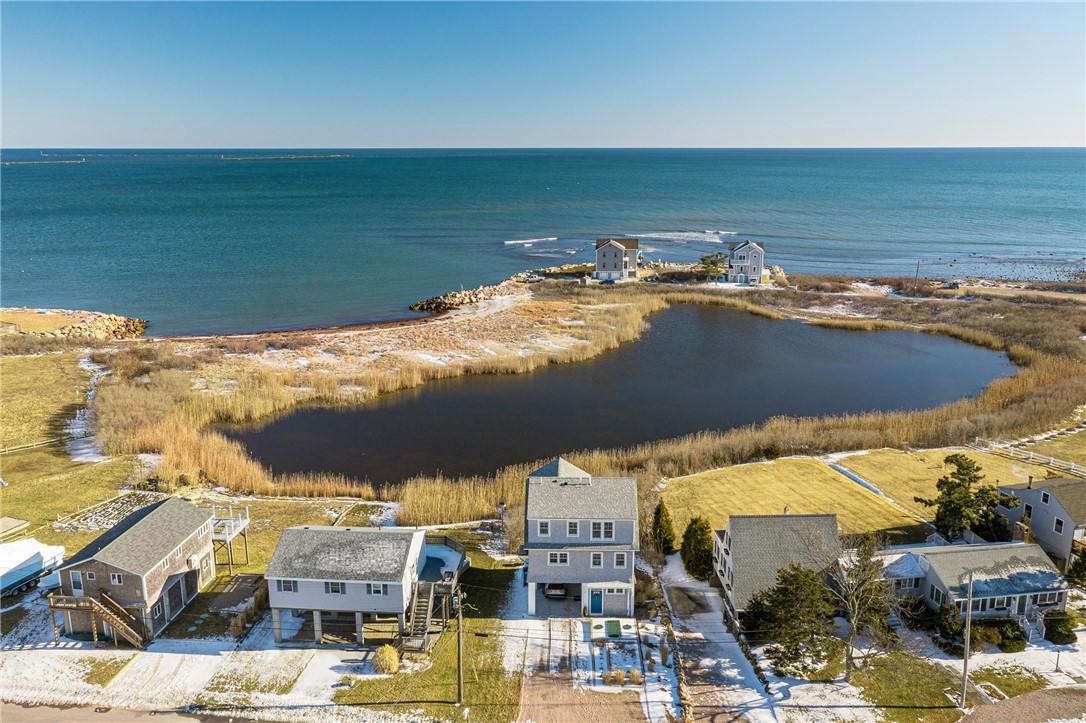 Aerial view of coastal homes beside a marsh pond and ocean.
