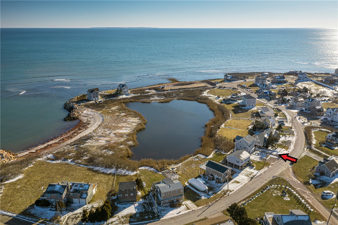 Coastal neighborhood aerial with ocean, marsh pond, and an arrow marking a house.
