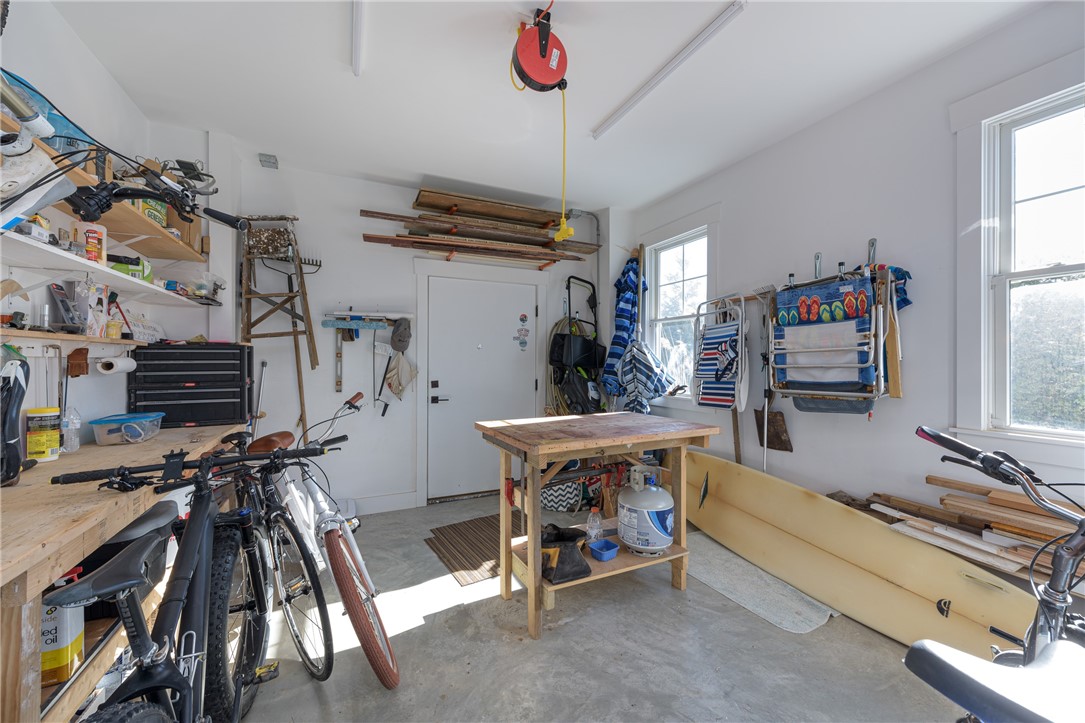 Garage with bicycles, a workbench, wall-mounted storage, and a kayak.