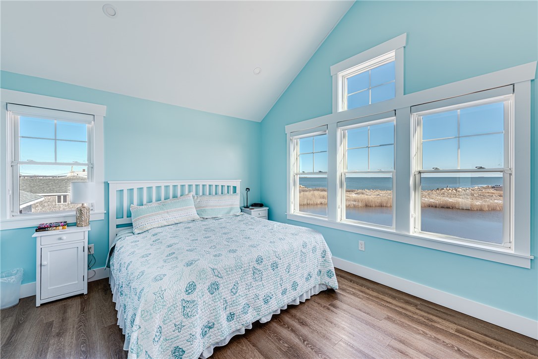 Bedroom with aqua walls and large windows overlooking a marsh and ocean.
