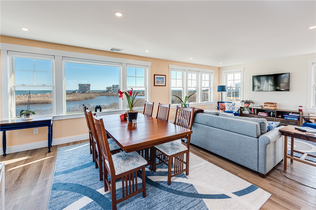 Open living and dining room with a gray sectional and broad windows overlooking coastal water and marsh.