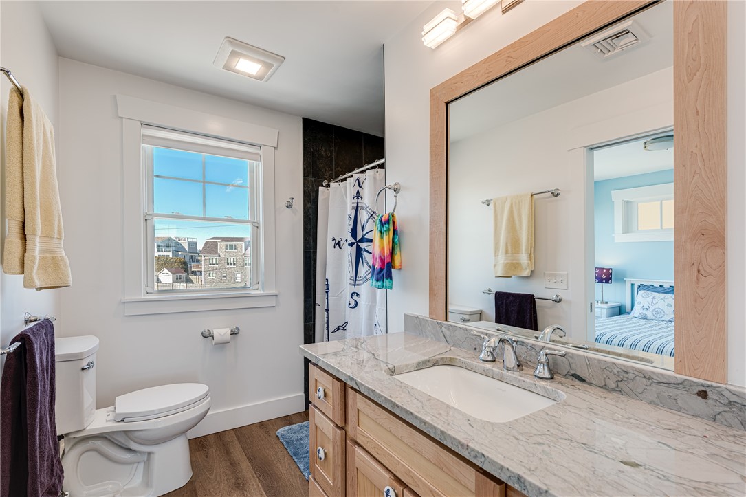 Bathroom with a marble vanity, large wood-framed mirror, and nautical-print shower curtain.