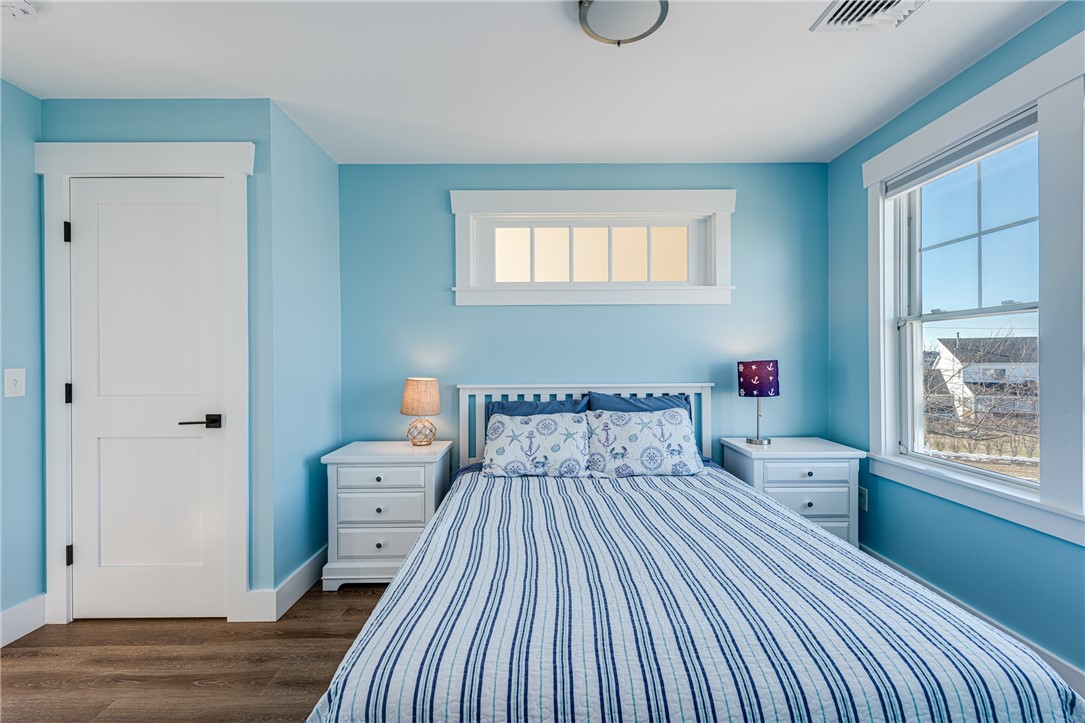 Bedroom with blue walls, striped bedding, matching nightstands, and a large window.