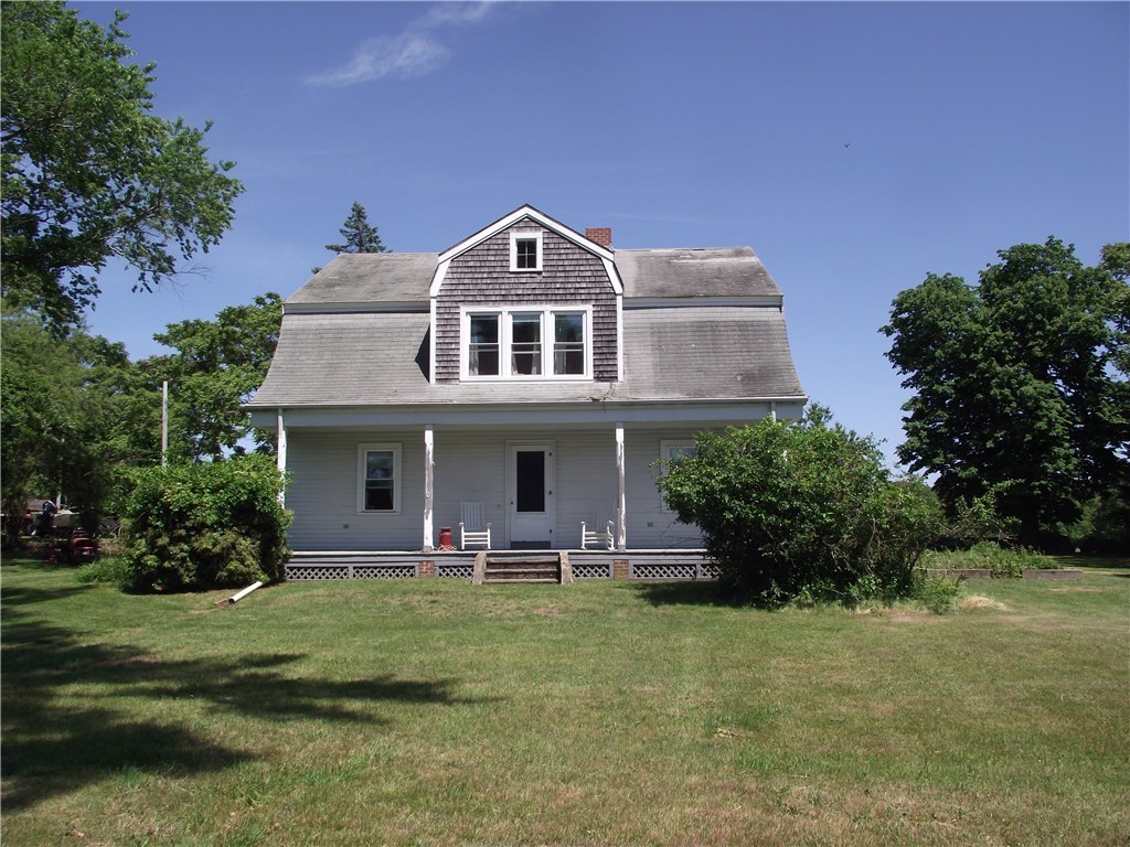 Gray two-story house with a large dormer, covered porch, and broad lawn.