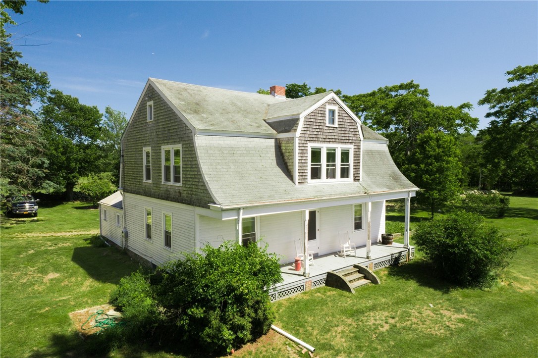 White two-story house with a gray gambrel roof and covered porch, viewed from above.