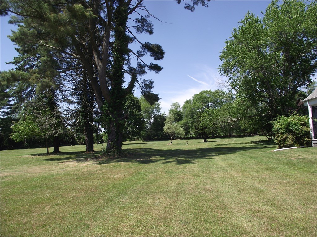 Spacious lawn shaded by mature trees, with part of the house visible at the edge.