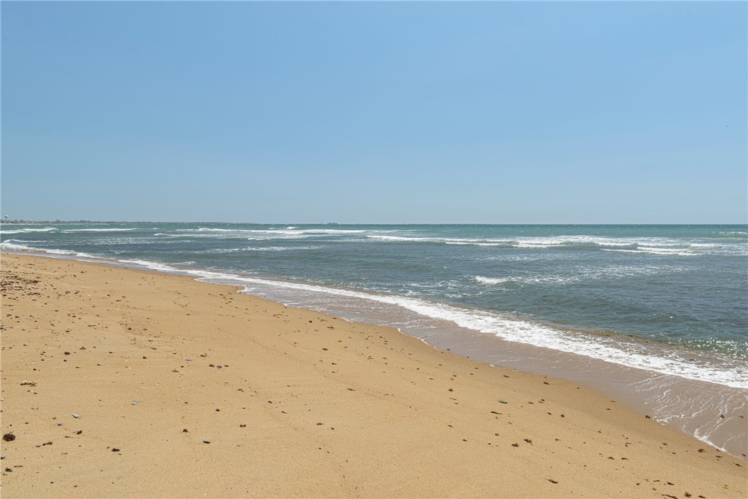 Sandy beach and rolling waves beneath a clear blue sky.